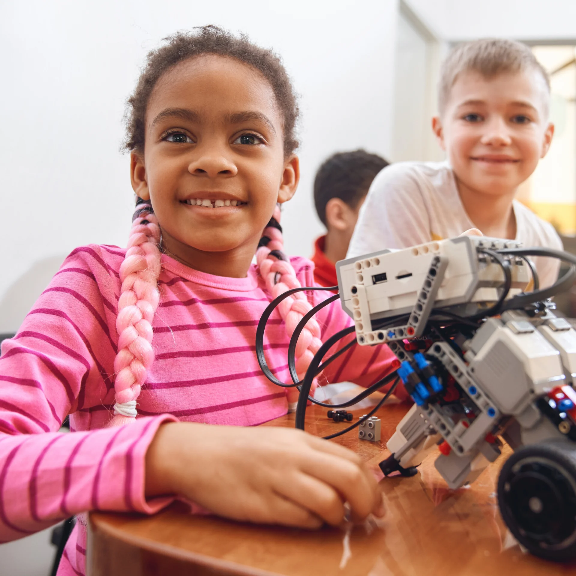 Crianças em uma aula de Robotica sorrindo para a câmera