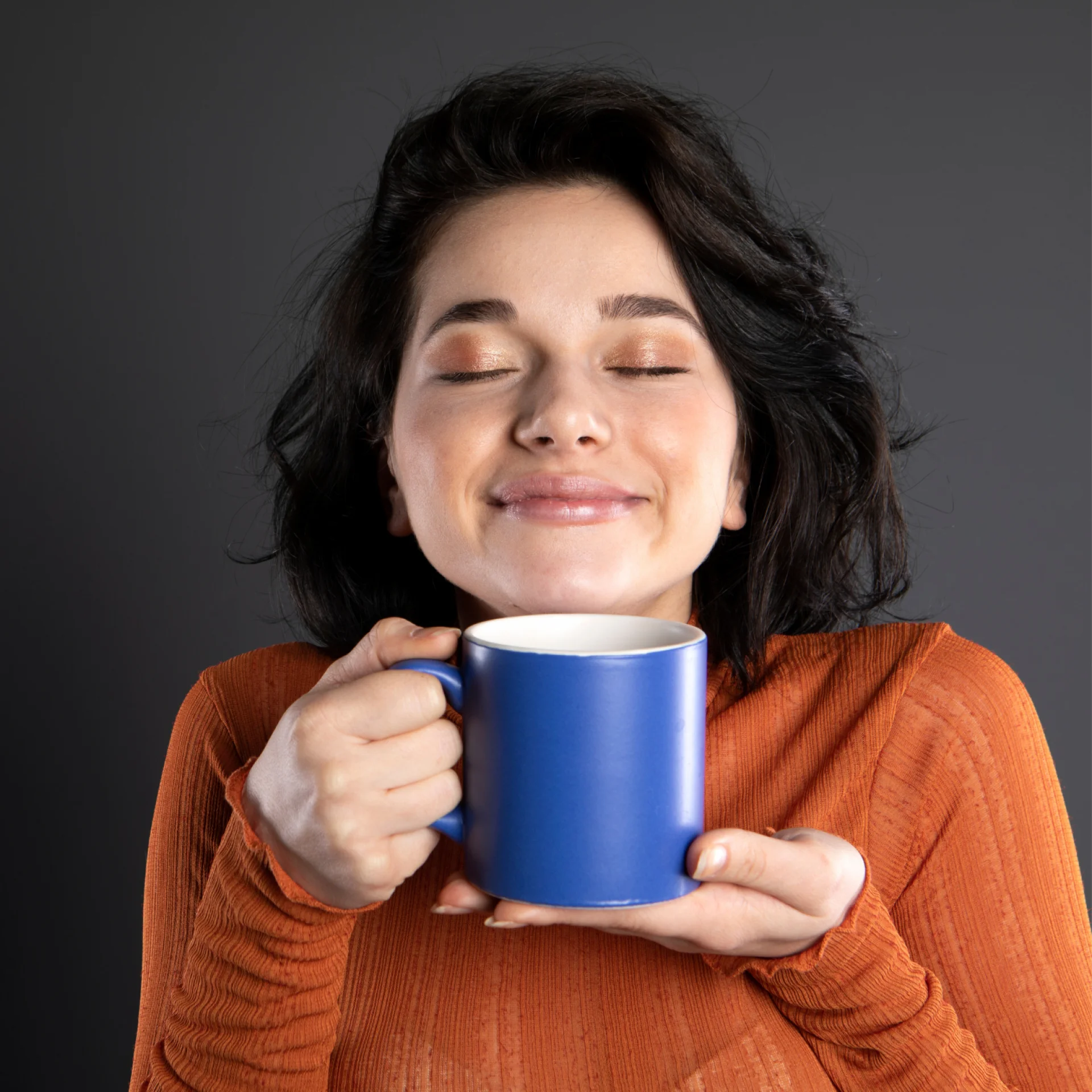 Mulher segurando uma xicara azul ccom café