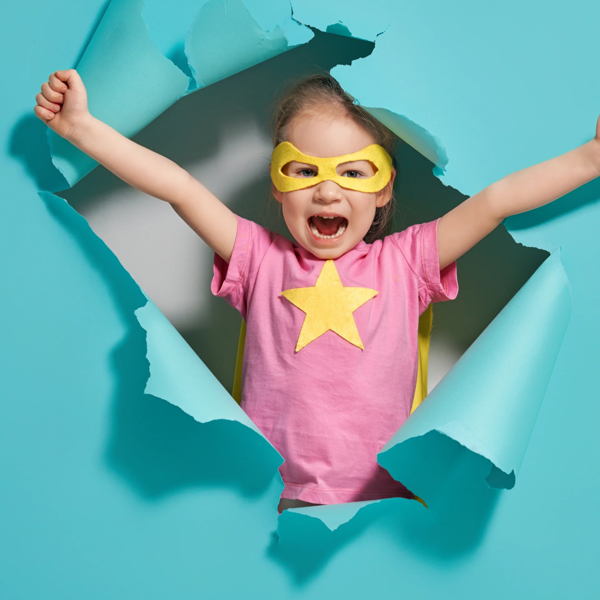 Criança com os braços para cima de camisa rosa e óculos de super herói amarelo Criança com os braços para cima de camisa rosa e óculos de super herói amarelo